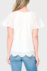Back view of Woman modeling Flutter Sleeve Scallop Top in White eyelet styled with denim