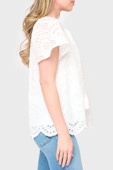 Side view of Woman modeling Flutter Sleeve Scallop Top in White eyelet styled with denim