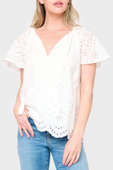 Woman modeling Flutter Sleeve Scallop Top in White eyelet styled with denim