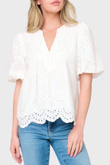 Woman modeling Bubble Sleeve Split Neck Top in White eyelet styled with denim