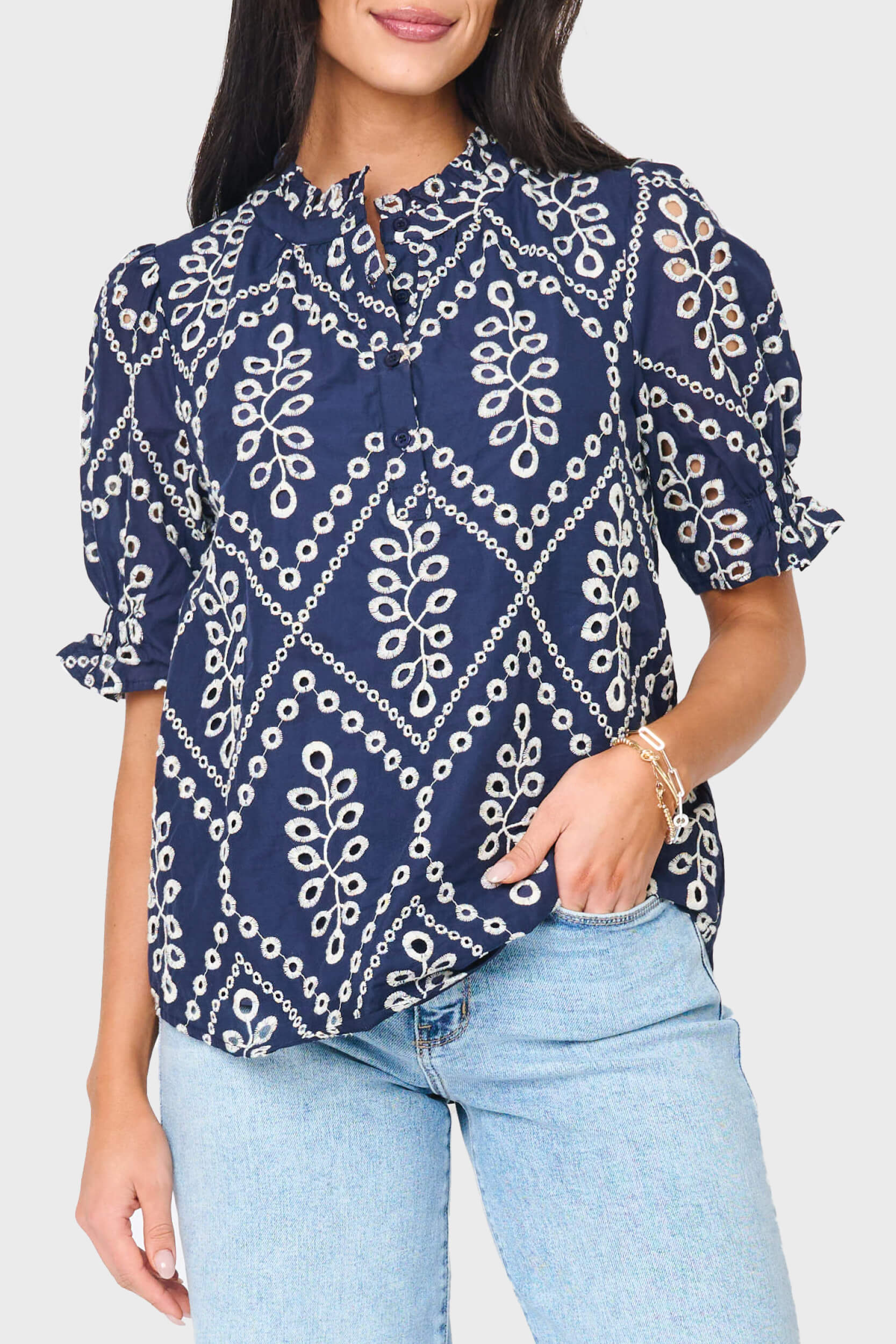 Woman modeling Dianthus Henley Puff Sleeve Eyelet Blouse in navy eyelet styled for work to weekend