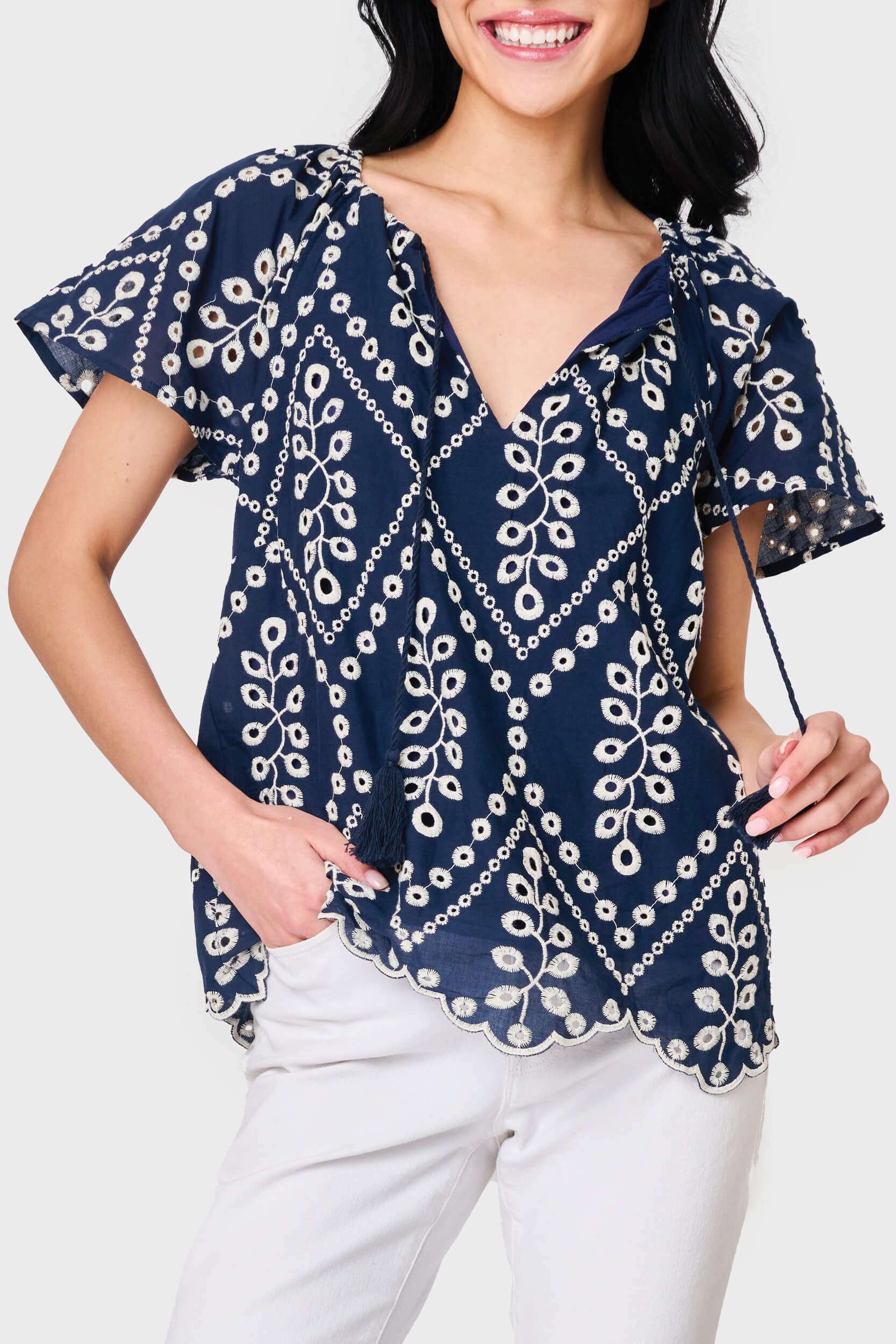 Woman modeling Flutter Sleeve Scallop Top in Navy Eyelet styled with casual pants