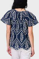 Back view of Woman modeling Flutter Sleeve Scallop Top in Navy Eyelet styled with casual pants