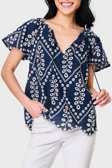 Woman modeling Flutter Sleeve Scallop Top in Navy Eyelet styled with casual pants