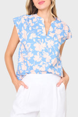 Woman modeling Cap Sleeve Notch Neck Blouse in Jardin Blue Floral styled for vacation and weekends