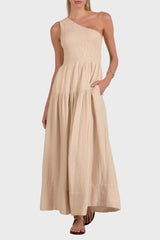 Woman wearing a beige one-shoulder dress against a white background