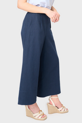 Side view of Woman modeling Wide Hem Cropped Linen Pant in Navy styled with blouse and sandals