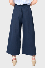 Back view of Woman modeling Wide Hem Cropped Linen Pant in Navy styled with blouse and sandals