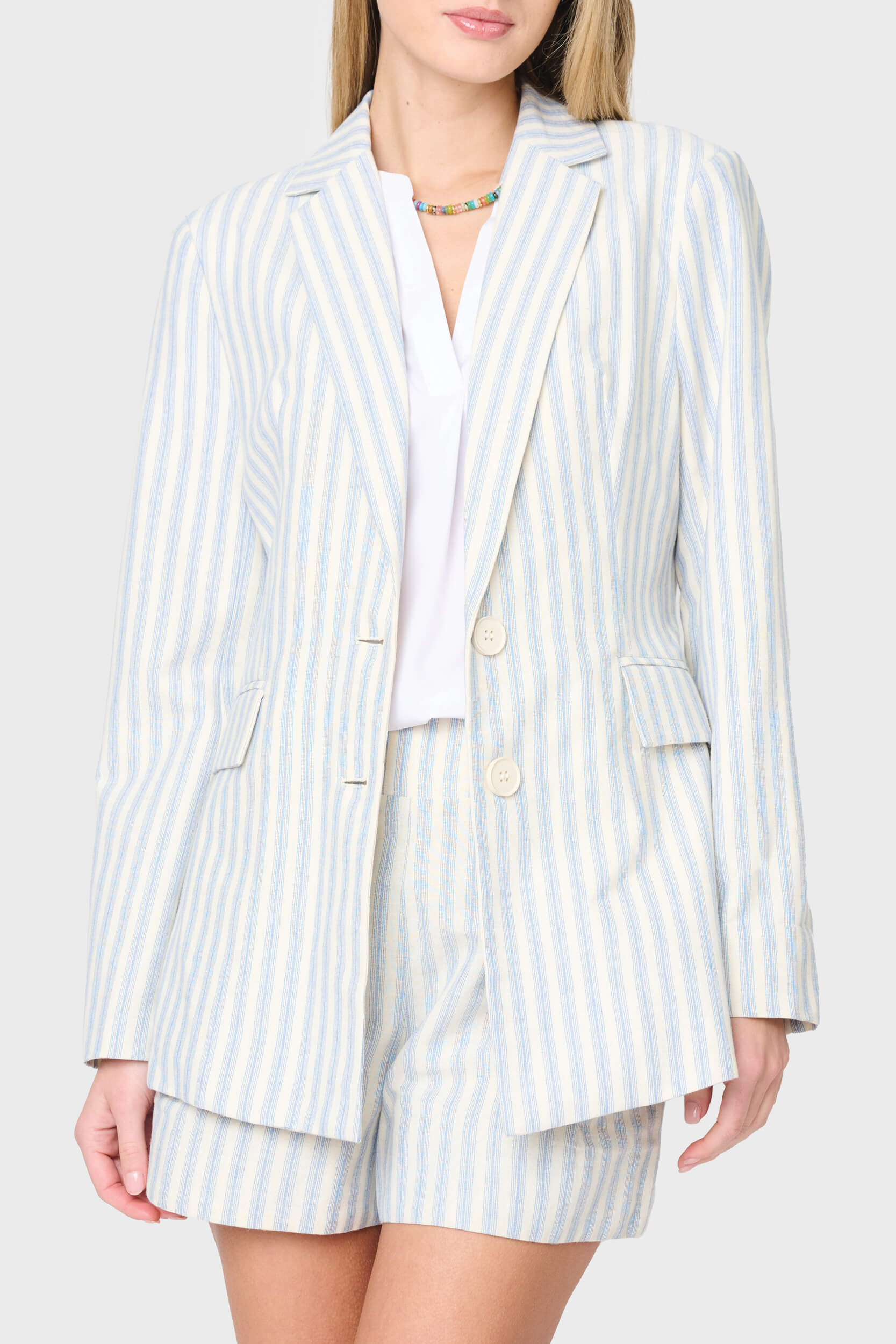 Woman modeling stripe linen blazer in blue ivory stripe styled as a set with matching shorts