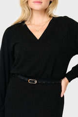 Woman wearing a black sweater with a belt against a white background