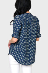 Back view of Woman modeling Dianthus Henley Puff Sleeve Blouse in Navy Daisy print styled with casual pants