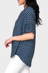 Side view of Woman modeling Dianthus Henley Puff Sleeve Blouse in Navy Daisy print styled with casual pants