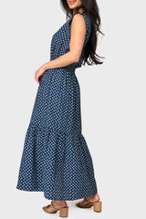 Side view of Woman modeling Lindsey Utility Maxi Dress in Navy Daisy print styled with sandals