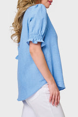 Side of Model wearing Dianthus Henley Puff Sleeve Blouse in textured Blue Skies, styled for summer