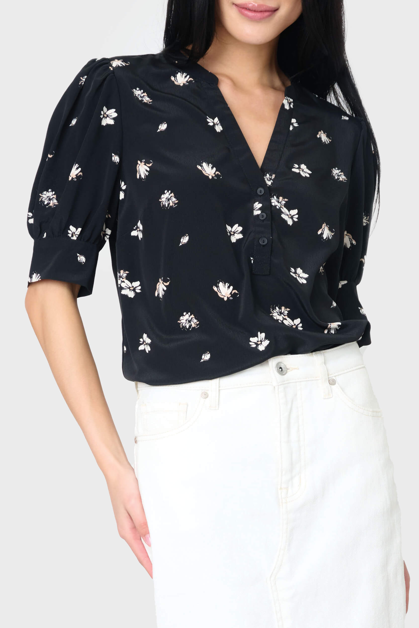 A black woven henley blouse with puff sleeves, floral print, paired with white trousers.
