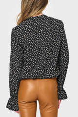 Back of Woman modeling Long Sleeve Surplice Blouse With Ruffle Sleeve in Black boho floral print styled for work