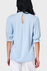 Back view of Woman modeling Feminine Mock Neck Luxe Sweater in Cashmere Blue styled with casual pants
