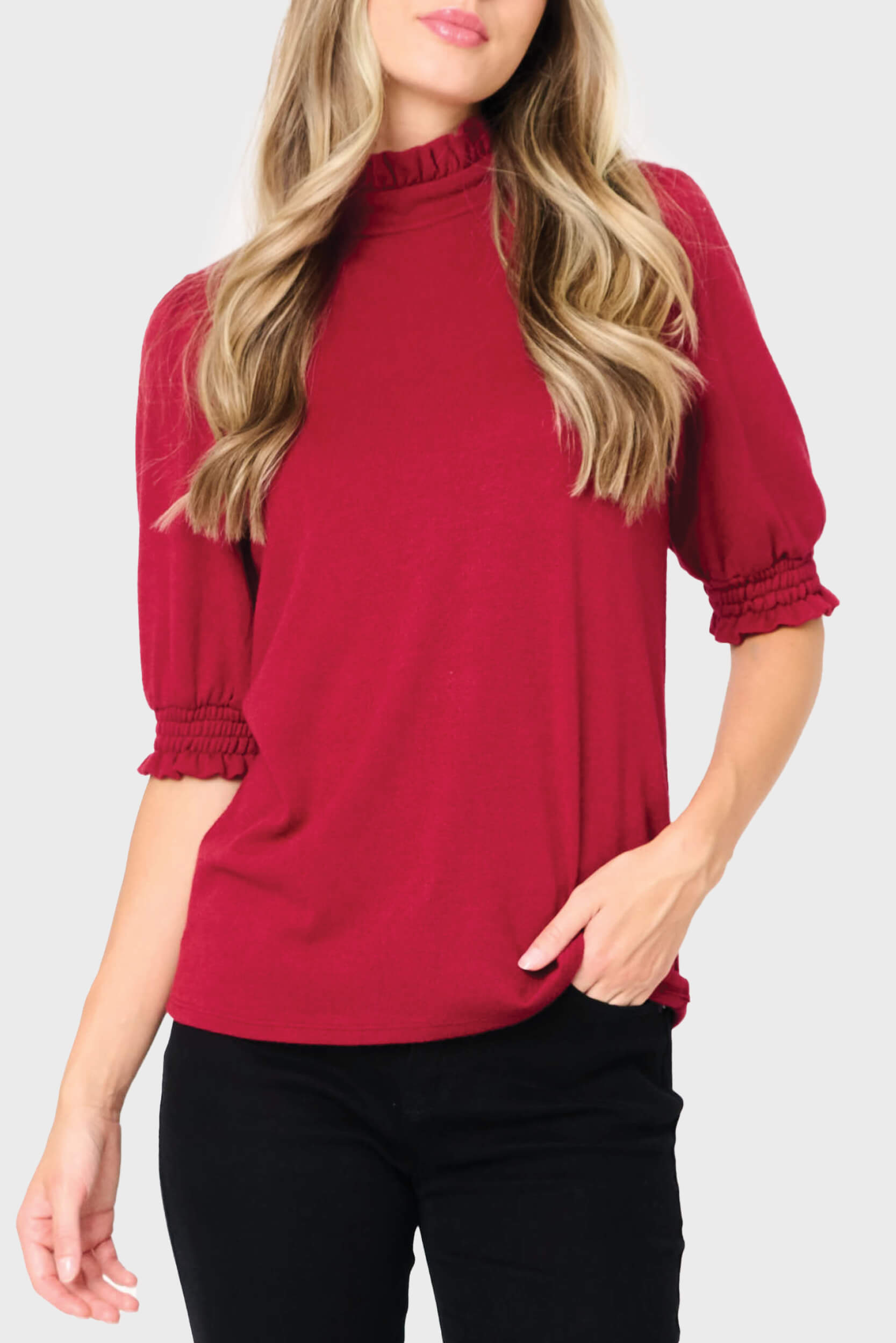 Woman wearing a red blouse with puff sleeves on a white background