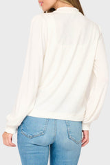 Person wearing a white sweater and blue jeans on a plain background