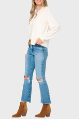 Woman wearing a white blouse, blue jeans, and brown boots on a white background