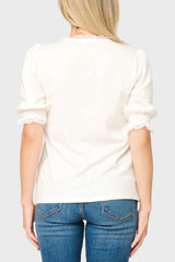Back of woman wearing a white sweater and blue jeans on a plain background
