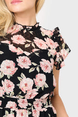 Woman wearing a black dress with pink floral pattern on a white background