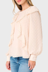 Light pink blouse with ruffled details worn by a woman on a light gray background