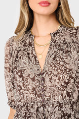 Close-up of a woman wearing a patterned blouse with layered necklaces on a white background
