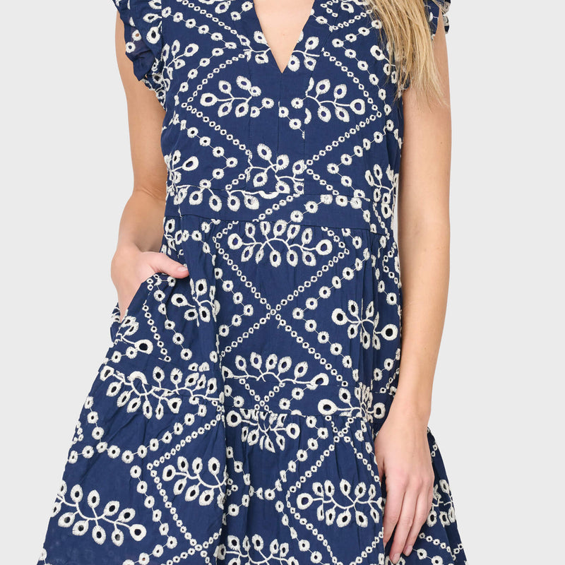 Woman modeling Flutter Sleeve Decked Out Day Dress in navy eyelet embroidery styled for warm weekends