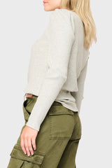 Person wearing a light gray ribbed sweater and green cargo pants on a plain background