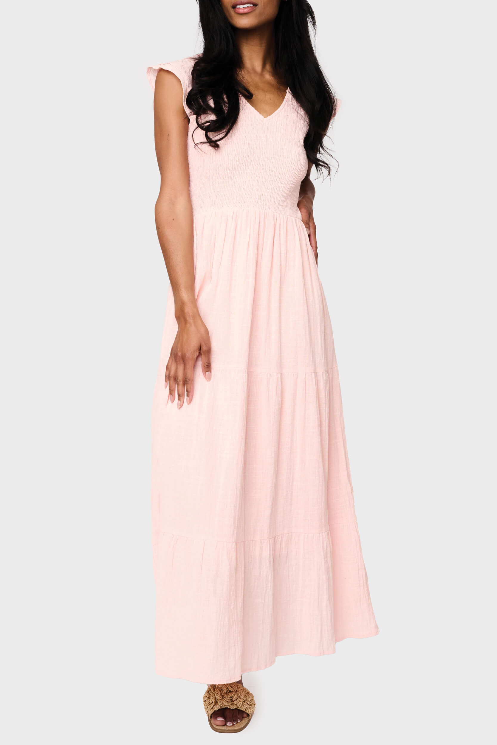 Woman modeling Flutter Sleeve Smocked V Neck Tiered Maxi Dress in Pearl blush pink, styled for vacation