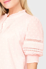 Close-up of a pink blouse with lace details on a plain background
