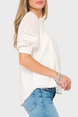 Woman wearing a white blouse with lace details and blue jeans on a white background