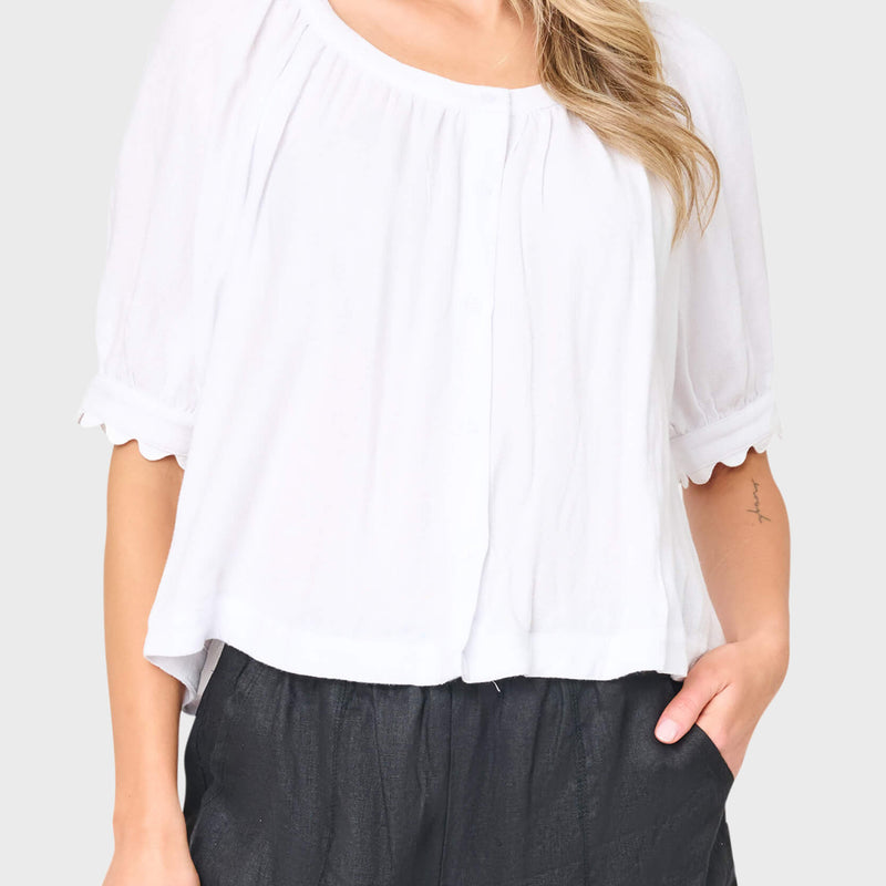 Woman modeling Lily Scallop Puff Sleeve Linen Top in White styled for vacation and weekends