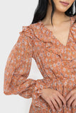 Close-up of women wearing the Moon River Smocked Ruffled Printed Maxi Dress in rust multi
