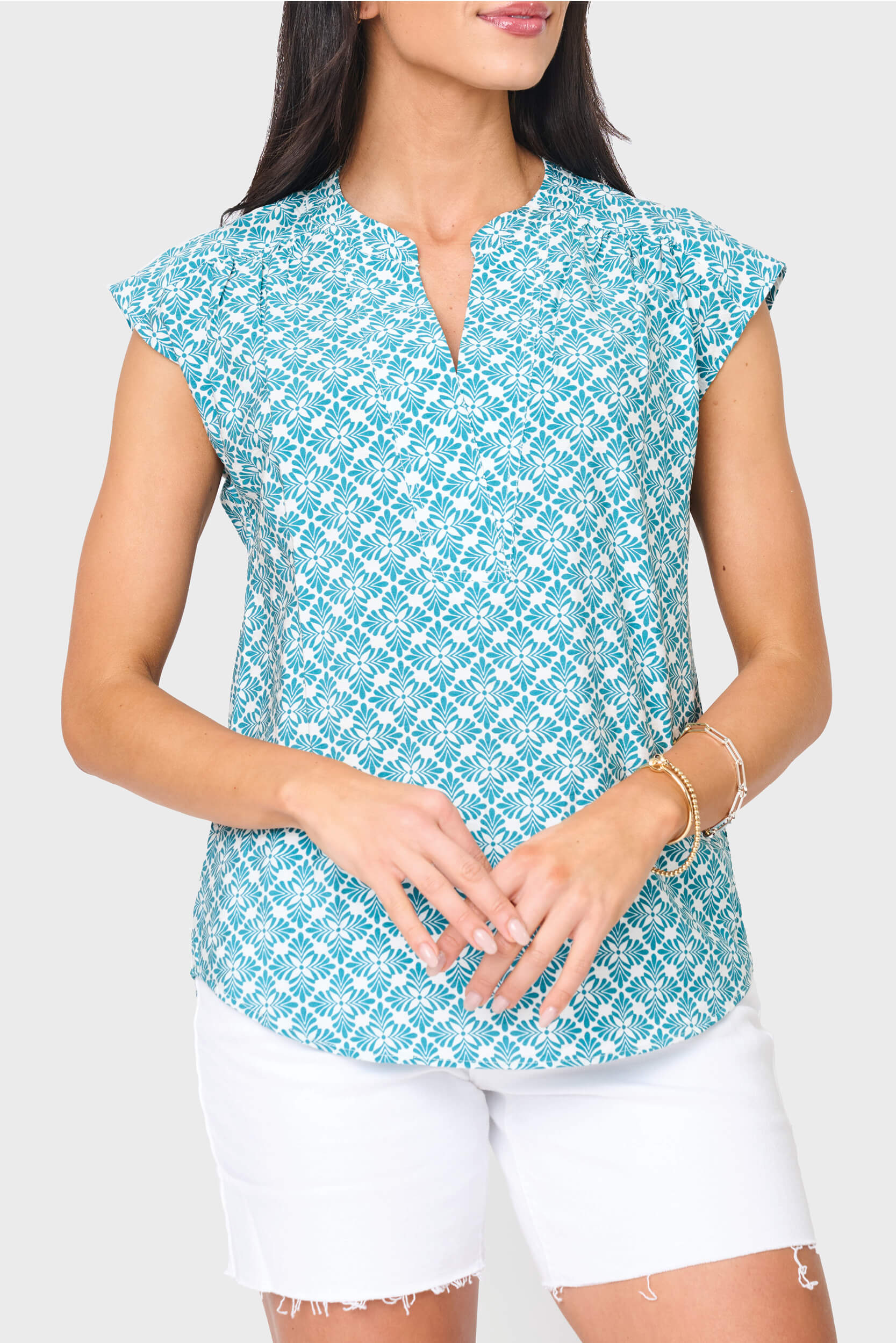Woman modeling Cap Sleeve Notch Neck Blouse in teal leaf tile green print styled for weekends and work