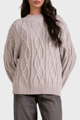 Woman wearing a cable knit sweater on a plain background