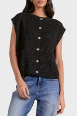 Woman wearing a black knitted vest with silver buttons on a white background