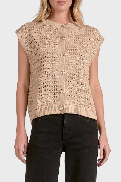 Woman wearing a beige knitted vest with button details on a white background