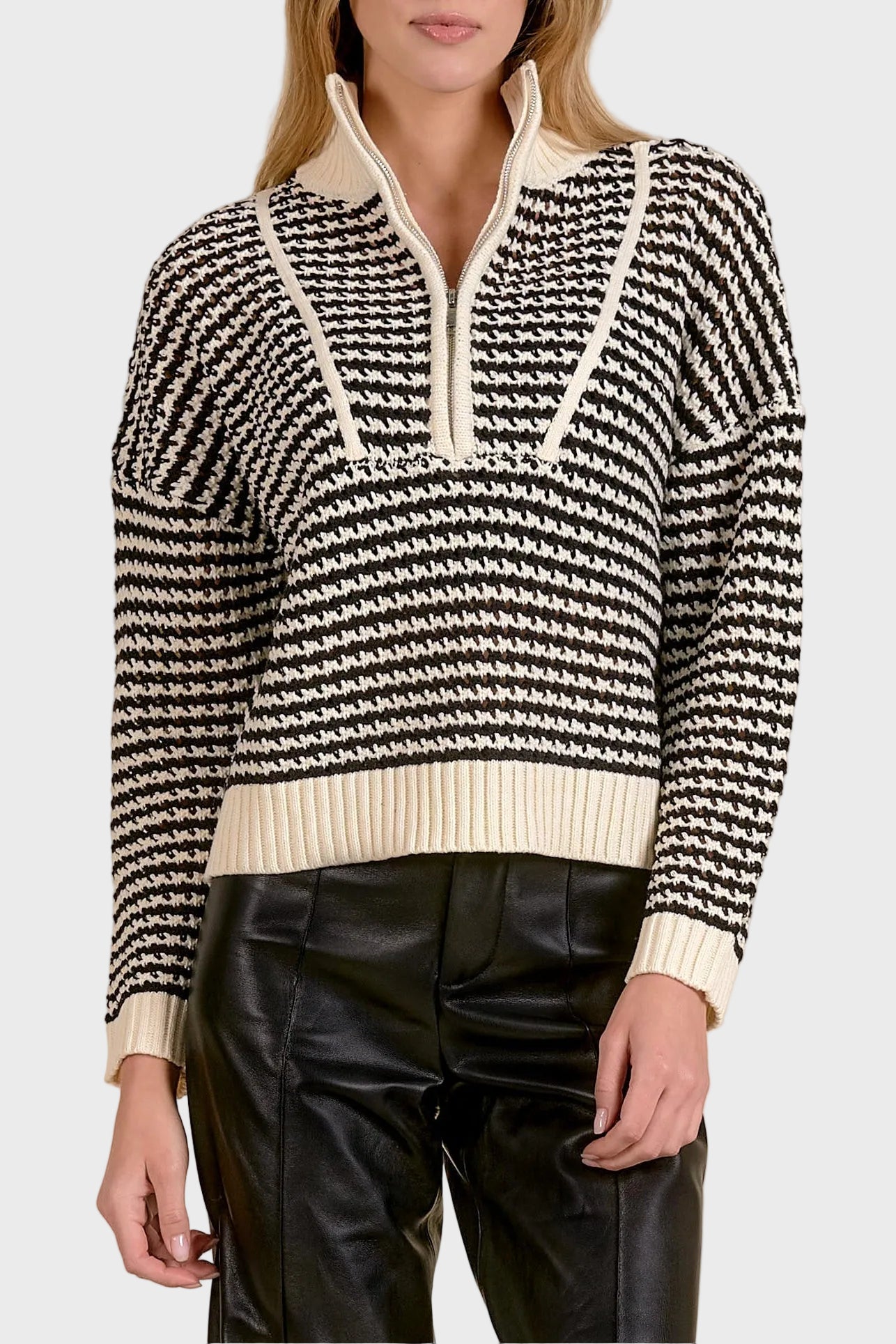 Woman wearing a black and white patterned sweater with a beige collar against a beige background