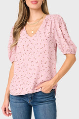 Woman wearing a pink floral blouse and blue jeans on a white background
